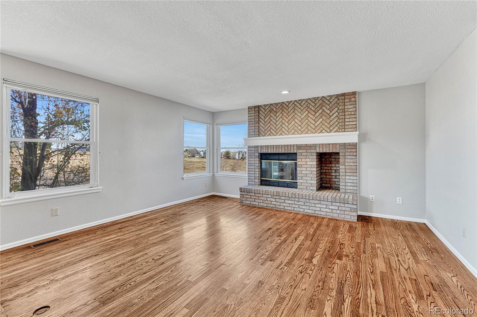 9858 Venneford Ranch Road Highlands Ranch, CO 80126 - Photo 18 of 50 an empty room with wooden floor fireplace and windows