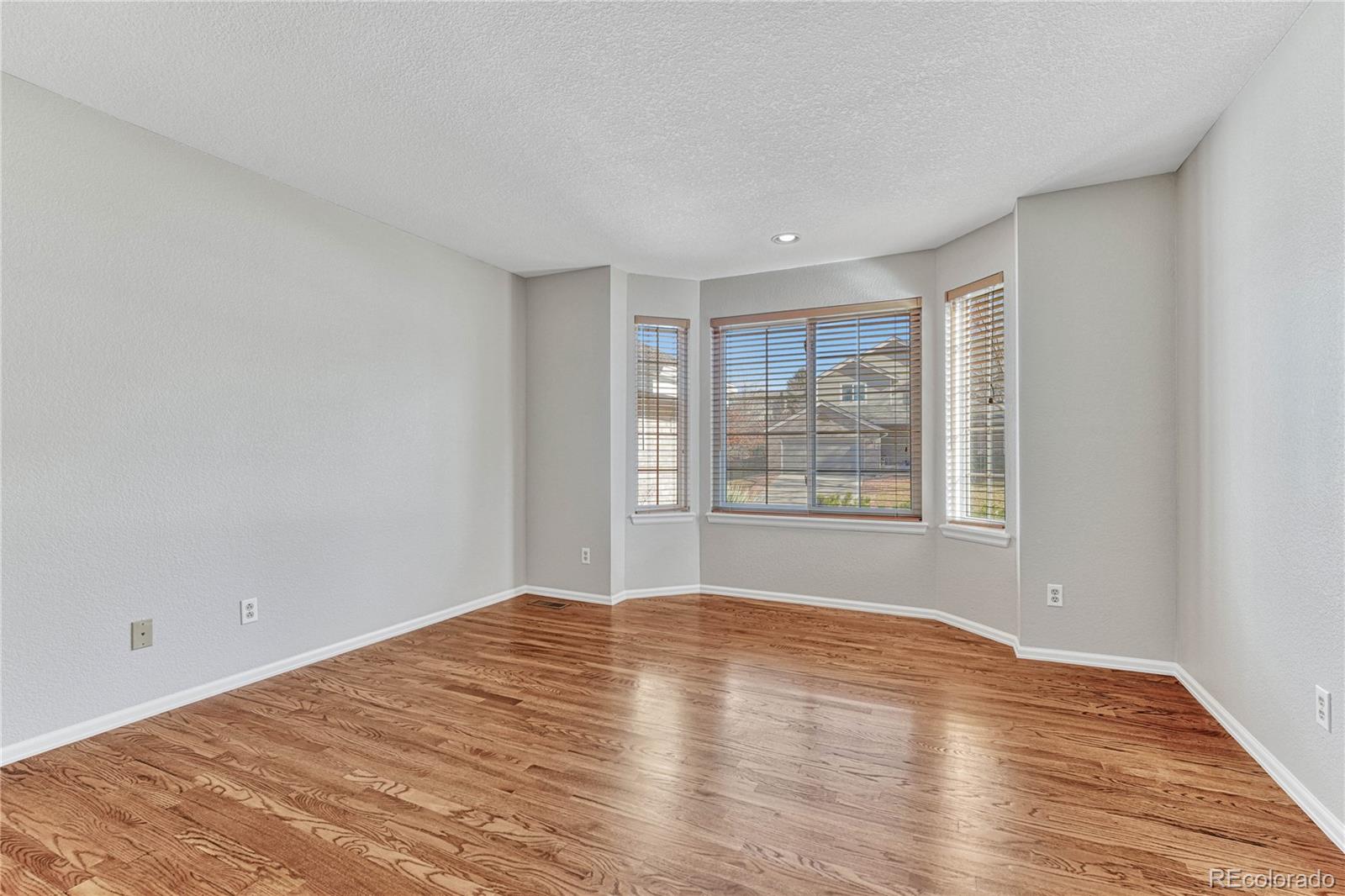 9858 Venneford Ranch Road Highlands Ranch, CO 80126 - Photo 26 of 50 a view of empty room with wooden floor and fan