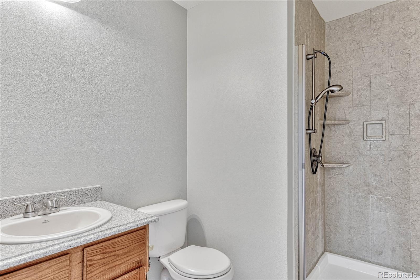 9858 Venneford Ranch Road Highlands Ranch, CO 80126 - Photo 27 of 50 a bathroom with a granite countertop toilet sink and shower