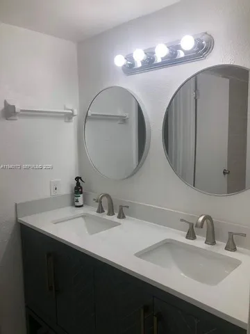 a bathroom with double vanity sinks and a mirror