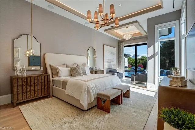 a spacious bedroom with a bed a chandelier and large mirror on the dresser