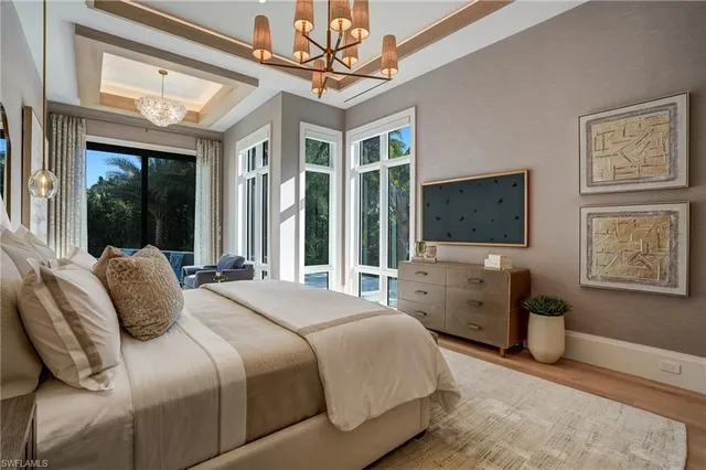 a bedroom with a large bed a flat tv screen and dresser