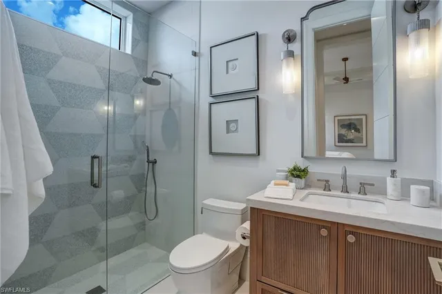 a bathroom with a toilet sink vanity granite and shower