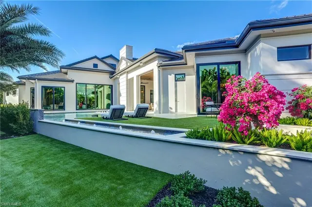 a front view of house and yard with beautiful flowers and green space