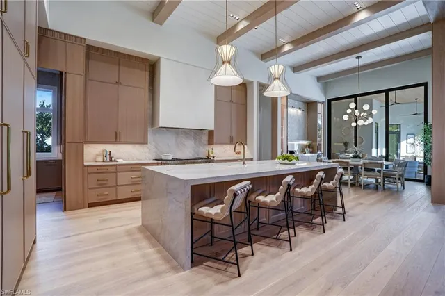 a large kitchen with cabinets chairs and wooden floor