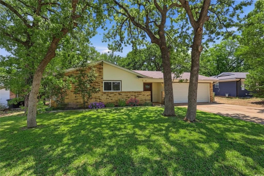 Single-story residence featuring a brick and siding exterior, an attached garage, and a lush green lawn