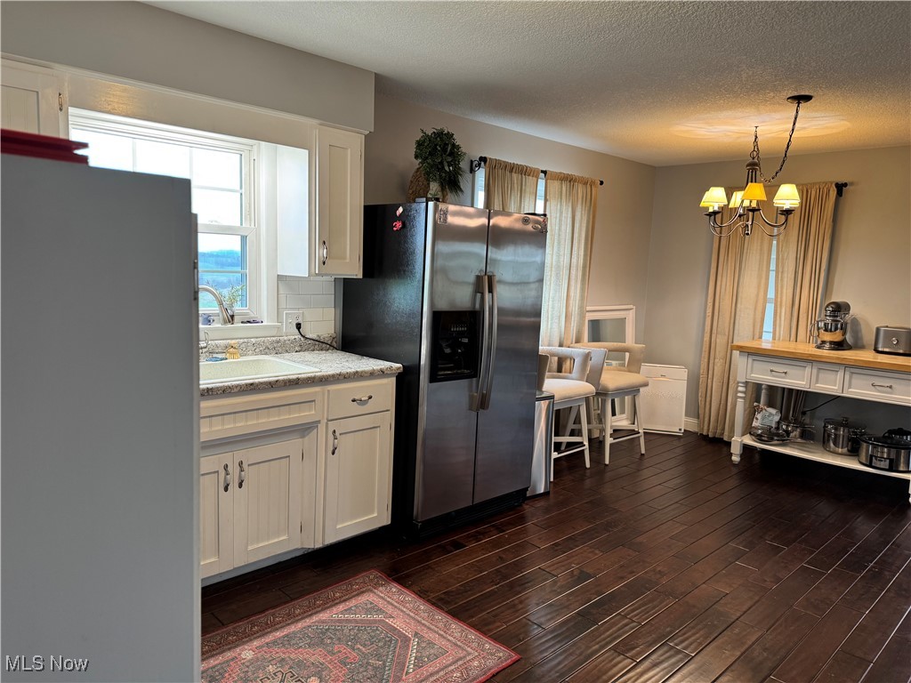 1790 Rix Mills Road New Concord, OH 43762 - Photo 11 of 28 Kitchen featuring a chandelier, dark wood-style floors, white cabinetry, stainless steel refrigerator with ice dispenser, and a sink