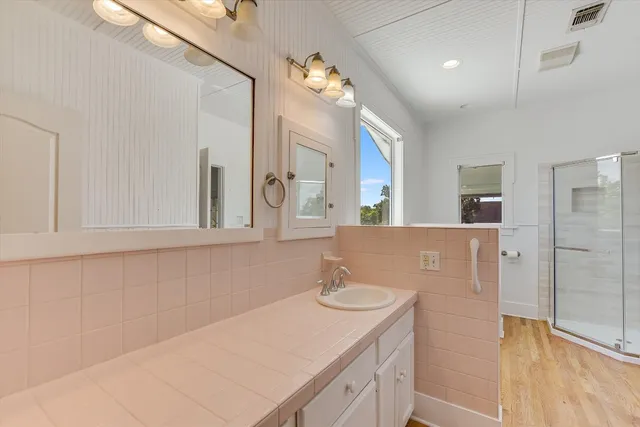 a bathroom with a sink vanity granite tub and a mirror