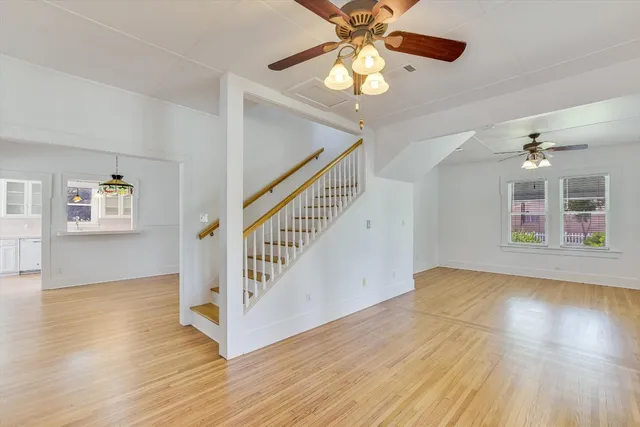 wooden floor in an empty room with a window and a chandelier fan