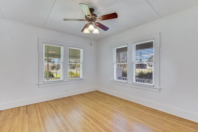 a view of an empty room with wooden floor and a window