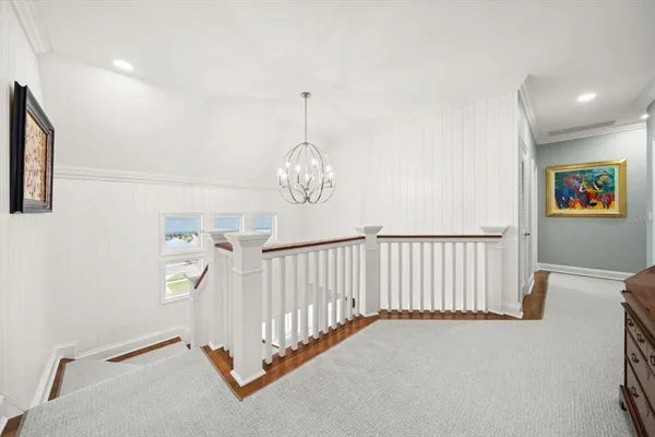 a view of a hallway to a livingroom with wooden floor and furniture