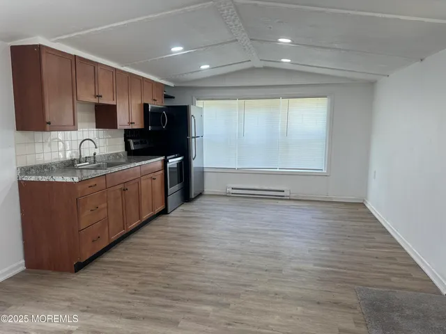 a kitchen with stainless steel appliances granite countertop a sink window and cabinets