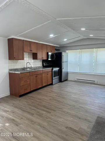 a large kitchen with stainless steel appliances a large counter top a stove and a refrigerator