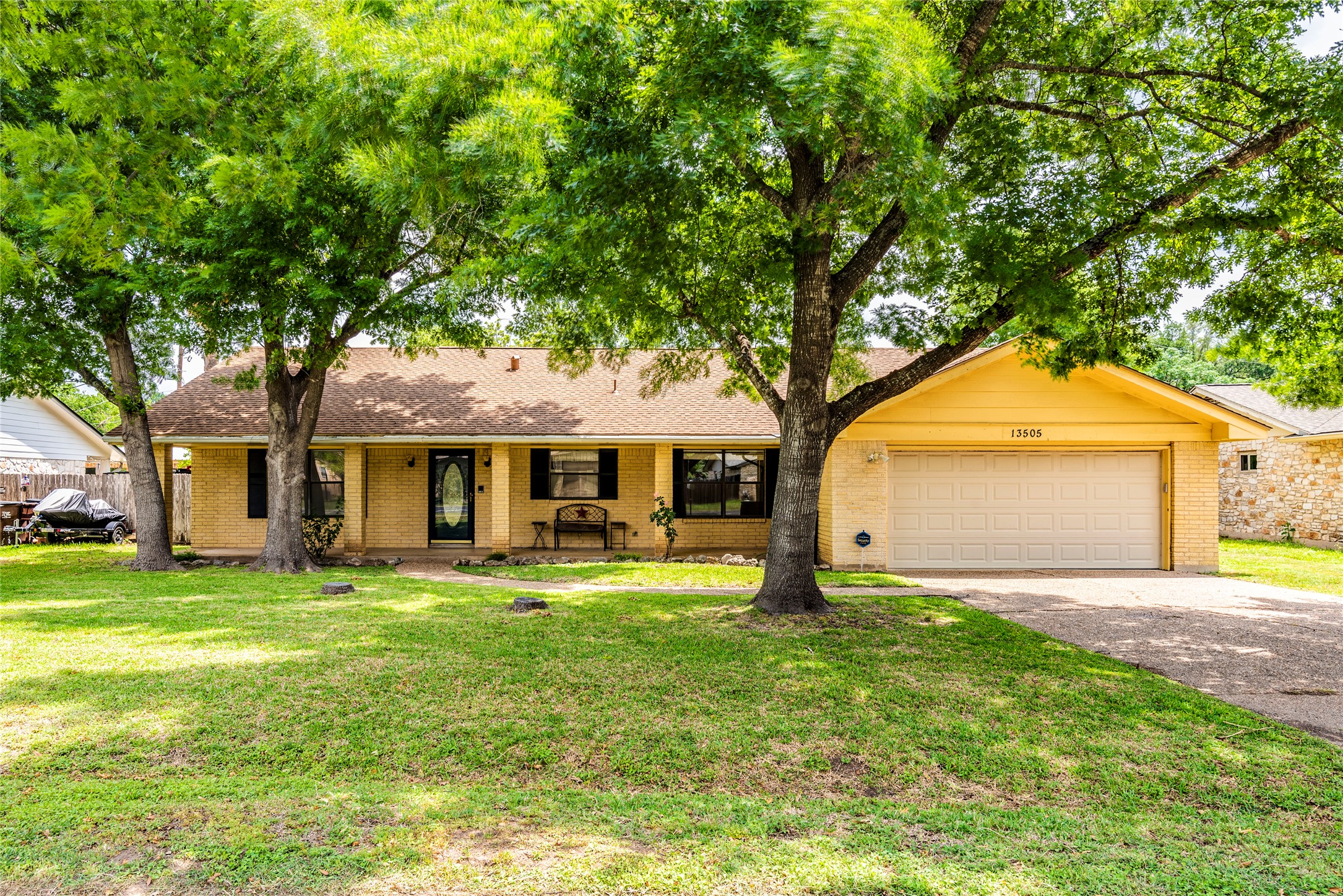 Single story home featuring a porch, a front lawn, brick siding, driveway, and an attached garage