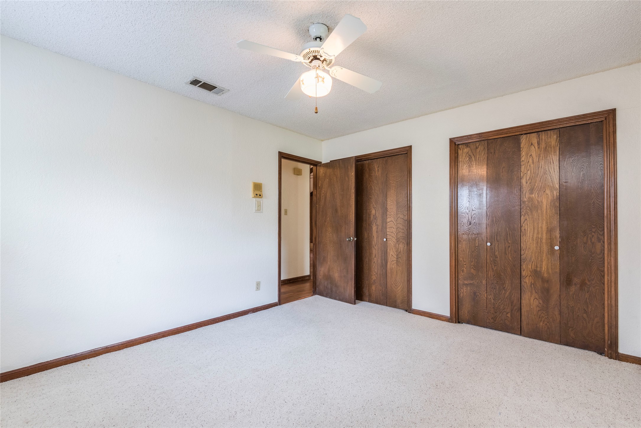 13505 Broadmeade Avenue Austin, TX 78729 - Photo 14 of 21 Unfurnished bedroom with two closets, carpet floors, a textured ceiling, and a ceiling fan