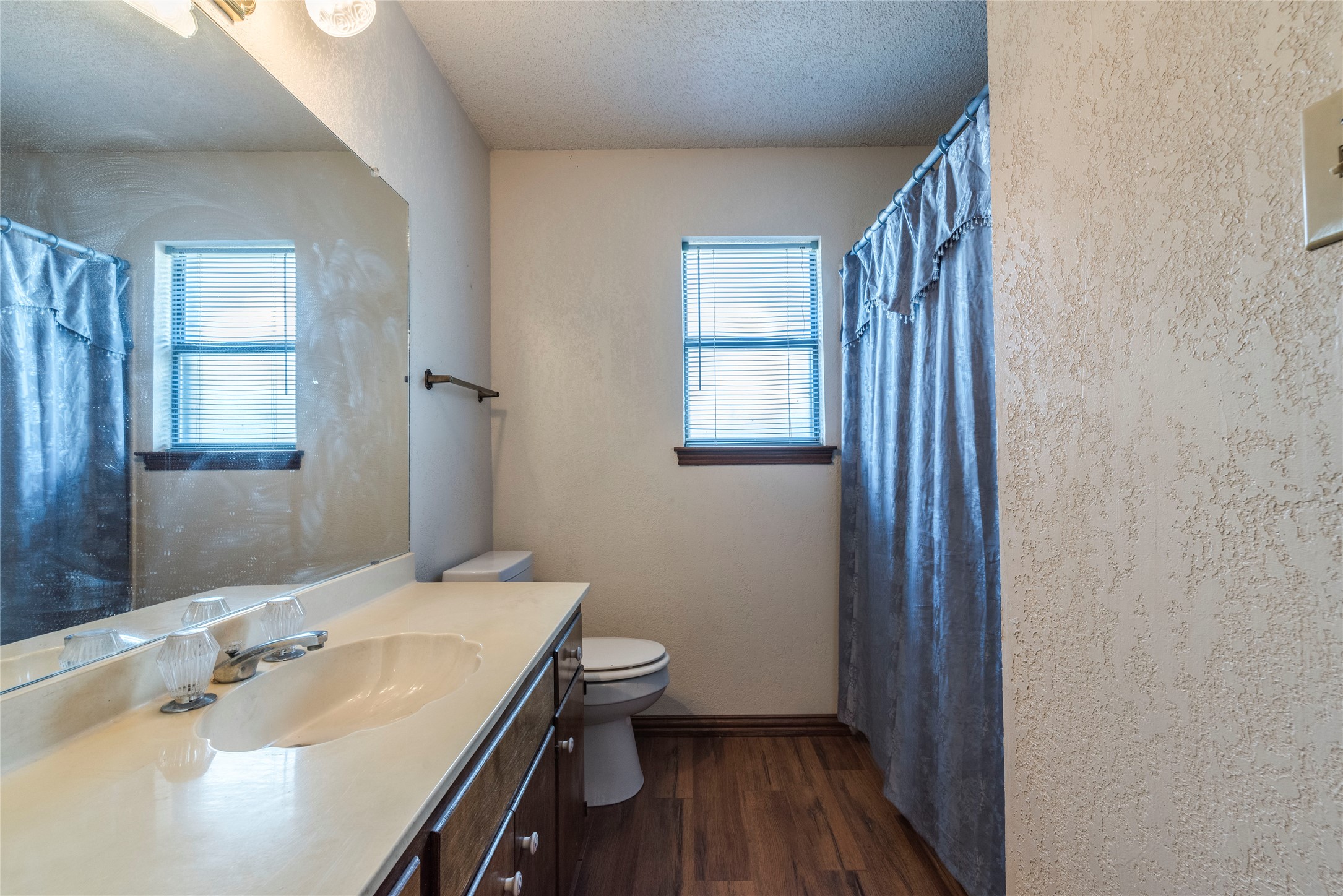 13505 Broadmeade Avenue Austin, TX 78729 - Photo 17 of 21 Full bathroom with vanity, a textured wall, dark wood-type flooring, healthy amount of natural light, and a textured ceiling