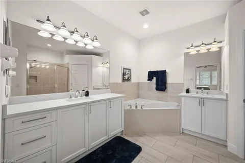 a spacious bathroom with a double vanity sink mirror and bathtub