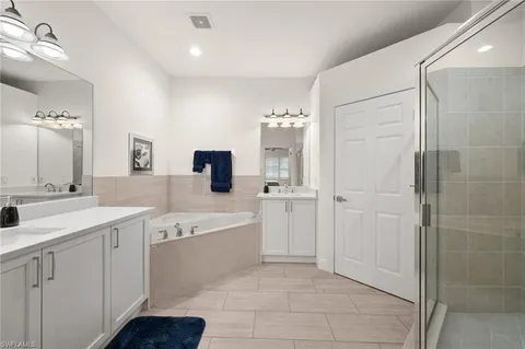 a spacious bathroom with a double vanity sink a mirror and a bathtub