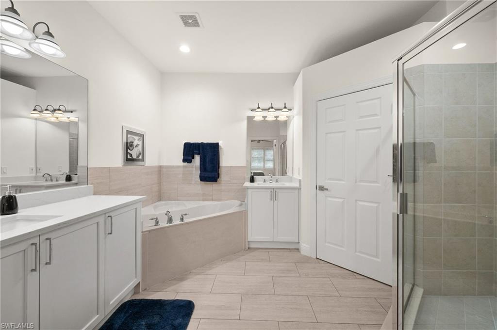 14562 Bellino Terrace, Unit 201 Bonita Springs, FL 34135 - Photo 19 of 46 a spacious bathroom with a double vanity sink a mirror and a bathtub