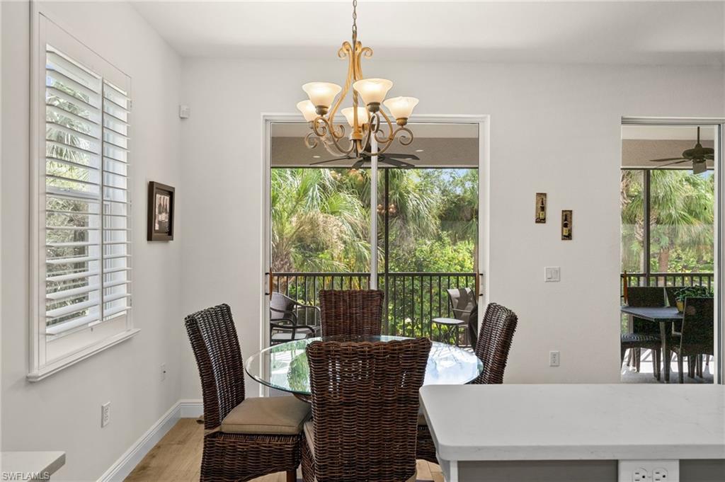 14562 Bellino Terrace, Unit 201 Bonita Springs, FL 34135 - Photo 9 of 46 a dining room with furniture a chandelier and wooden floor