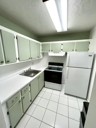 a kitchen with a sink a stove top oven and white cabinets