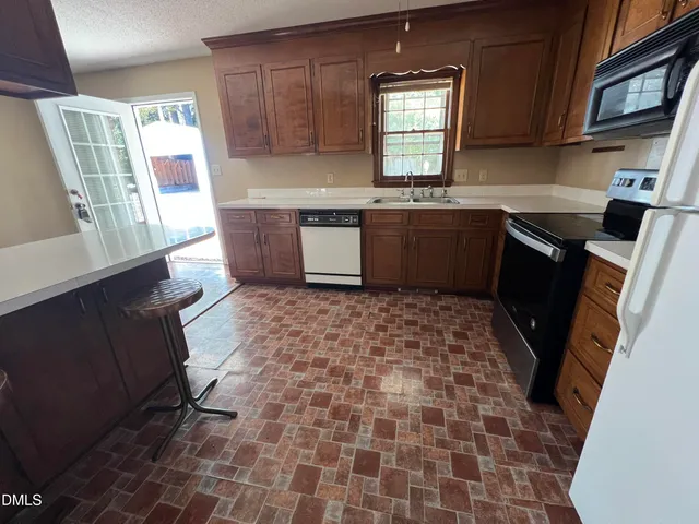 a kitchen with a sink a stove a refrigerator cabinets and a window
