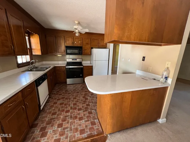 a kitchen with stainless steel appliances a stove a sink a microwave a refrigerator and cabinets