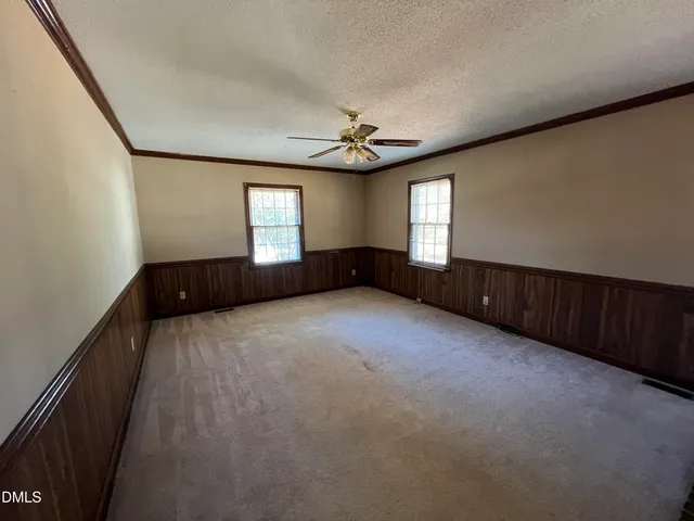 an empty room with windows and ceiling fan