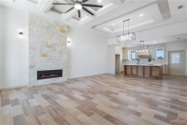 an empty room with kitchen view and a fireplace