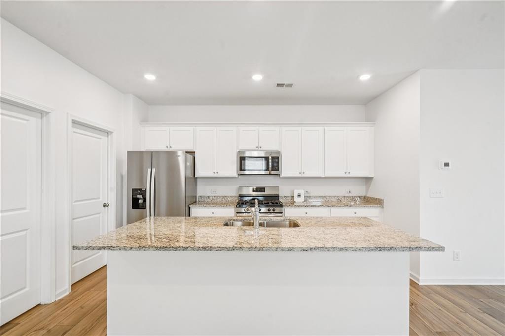 3853 Rustic Barn Way Loganville, GA 30052 - Photo 4 of 22 a kitchen with stainless steel appliances granite countertop a sink and a refrigerator