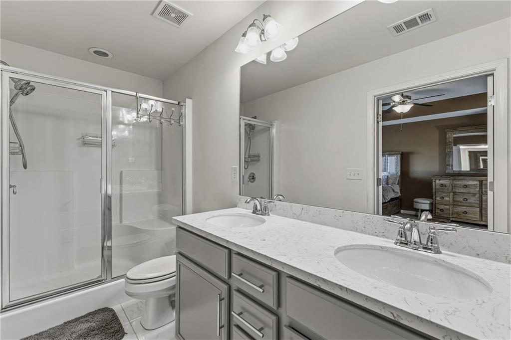 2275 Rolling Trail Lithonia, GA 30058 - Photo 17 of 38 a bathroom with a granite countertop sink toilet a large mirror a shower and vanity
