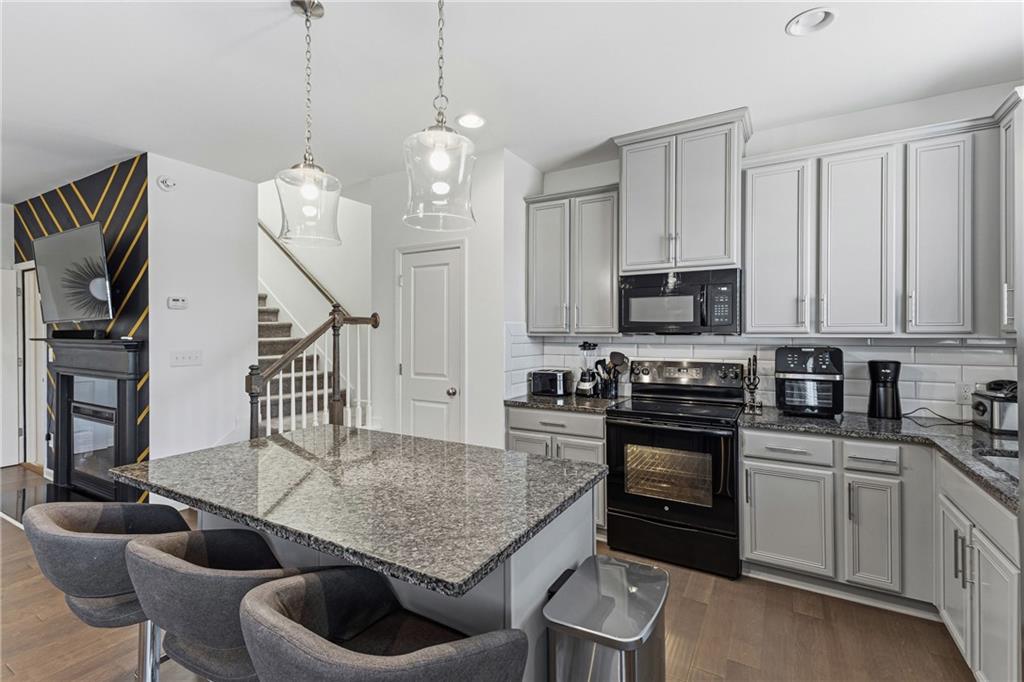 2275 Rolling Trail Lithonia, GA 30058 - Photo 5 of 38 a kitchen with stainless steel appliances granite countertop a stove a sink dishwasher a dining table and chairs with wooden floor