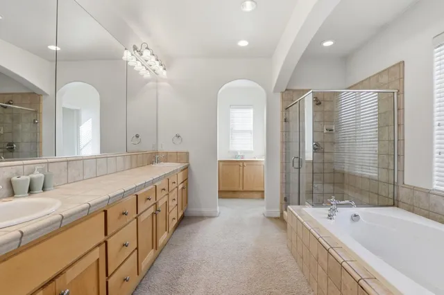 a bathroom with a double vanity sink a mirror a bathtub and shower