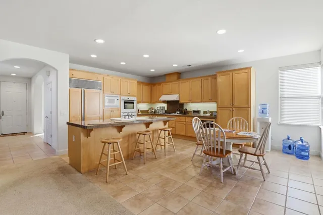 a kitchen with stainless steel appliances kitchen island granite countertop a refrigerator a stove a sink a table and chairs