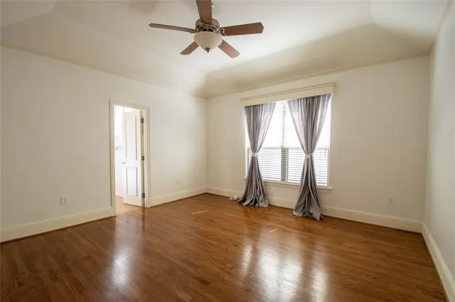 an empty room with wooden floor cabinet and windows