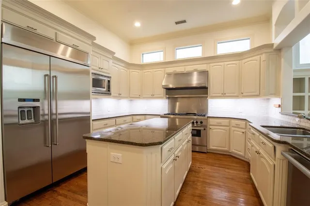a kitchen with stainless steel appliances granite countertop a sink a stove and a refrigerator