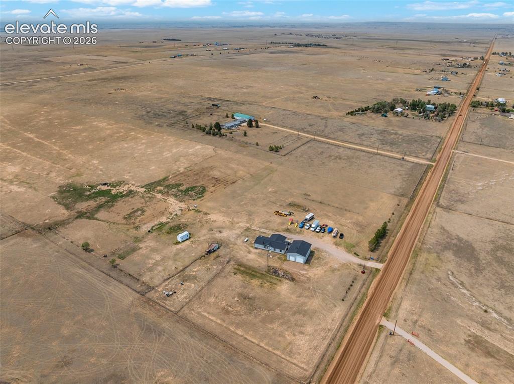 1350 South Calhan Highway Yoder, CO 80864 - Photo 7 of 45 Expansive rural property featuring a main residence with a dark gray roof, an attached garage, and additional outbuildings