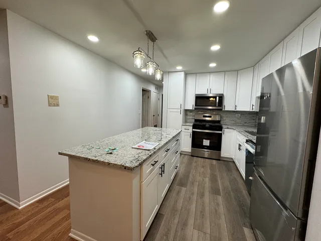 a large kitchen with stainless steel appliances granite countertop a stove refrigerator and a sink