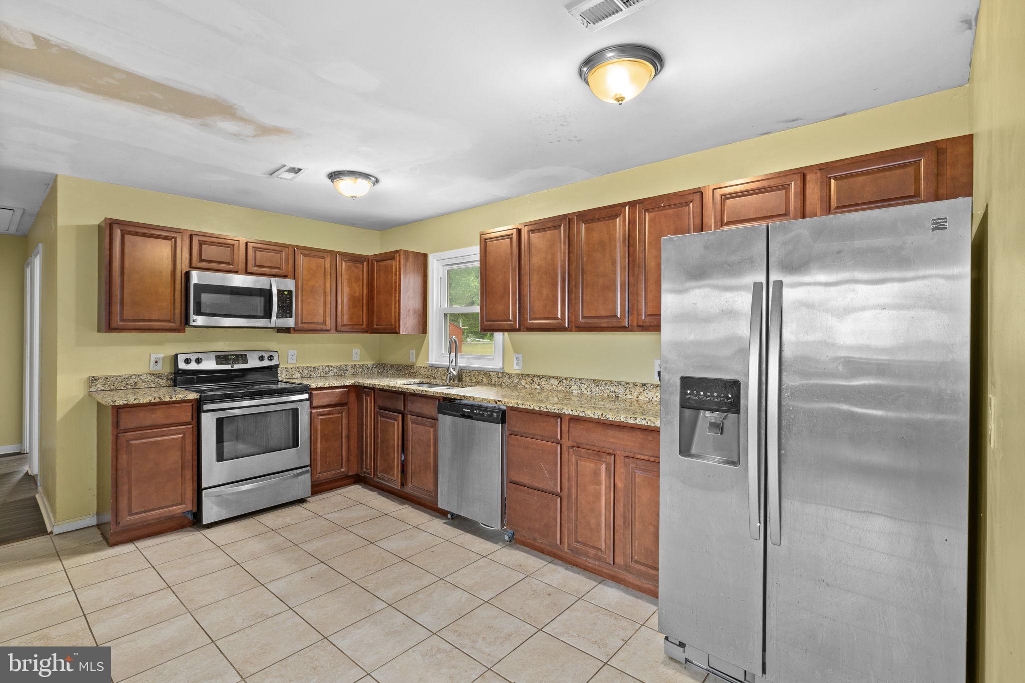 13245 Glen Level Drive Ruther Glen, VA 22546 - Photo 12 of 37 a kitchen with granite countertop a refrigerator and a stove top oven