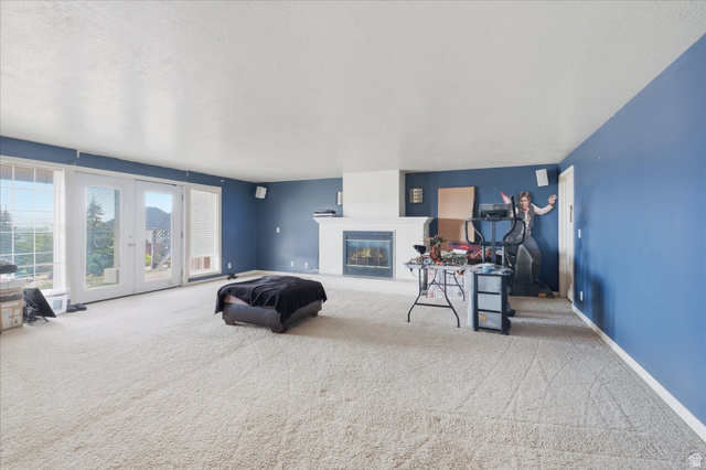 2887 View Crest Circle North Logan, UT 84341 - Photo 27 of 37 Carpeted living room with french doors, a glass covered fireplace, and a textured ceiling