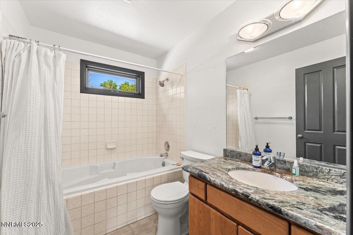 5455 Wild Horse Road Reno, NV 89510 - Photo 23 of 33 a bathroom with a granite countertop sink a toilet a mirror a bathtub and shower