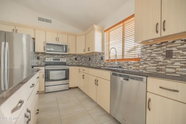a kitchen with stainless steel appliances granite countertop white cabinets a sink and a window