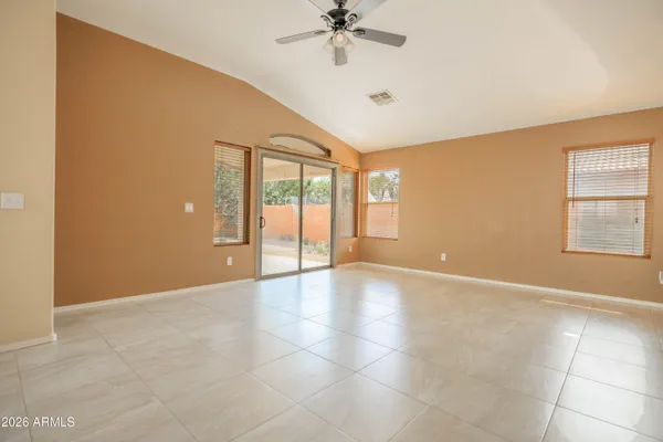an empty room with chandelier fan and windows
