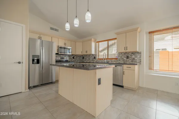 a kitchen with kitchen island granite countertop appliances cabinets and a window