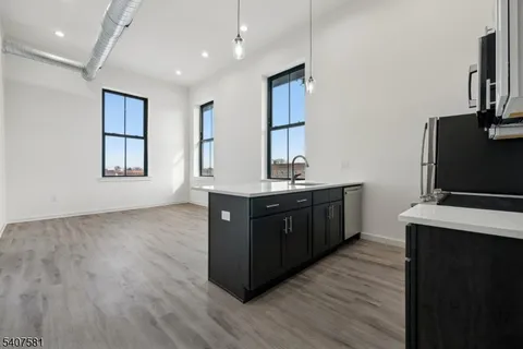 a kitchen with stainless steel appliances granite countertop a refrigerator a sink dishwasher and wooden floor