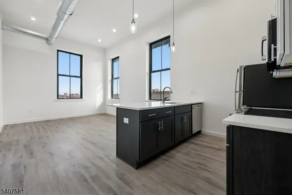 a kitchen with stainless steel appliances granite countertop a refrigerator a sink dishwasher and wooden floor