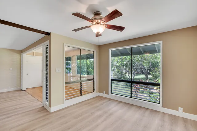a view of an empty room with wooden floor and a ceiling fan