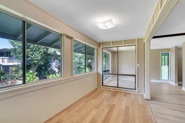 a view of empty room with wooden floor and fan