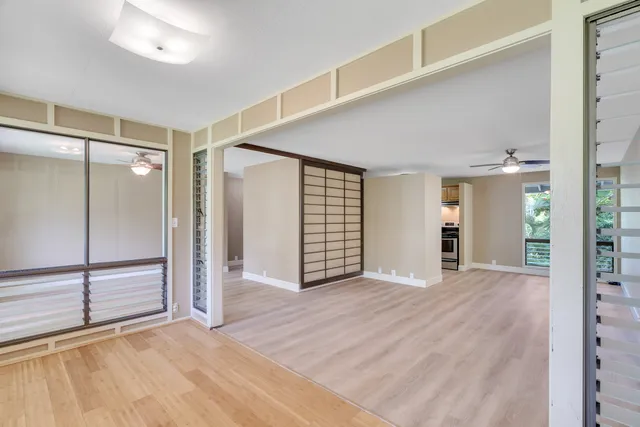 a view of an empty room with window and wooden floor