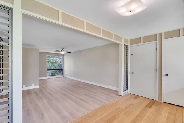 a view of an empty room with wooden floor and a window